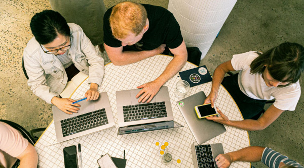 Eine Gruppe jüngerer Leute beim Arbeiten an einem Tisch mit Laptops