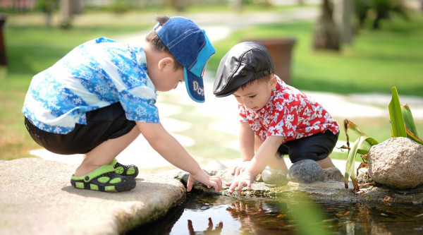 Zwei Jungs spielen am Rand eines Teichs